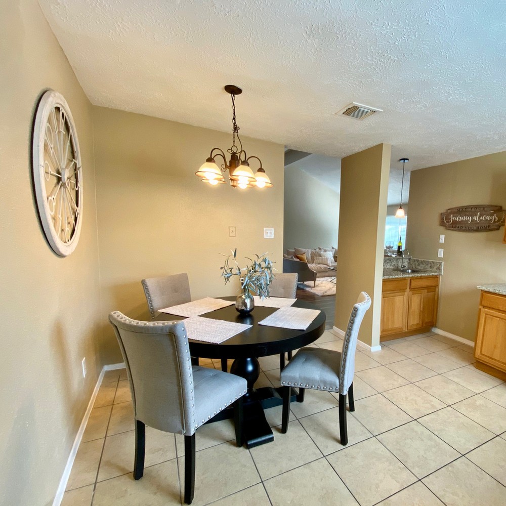 Breakfast room with black wooden table. Four gray chairs around the table. White placemats for each chair.