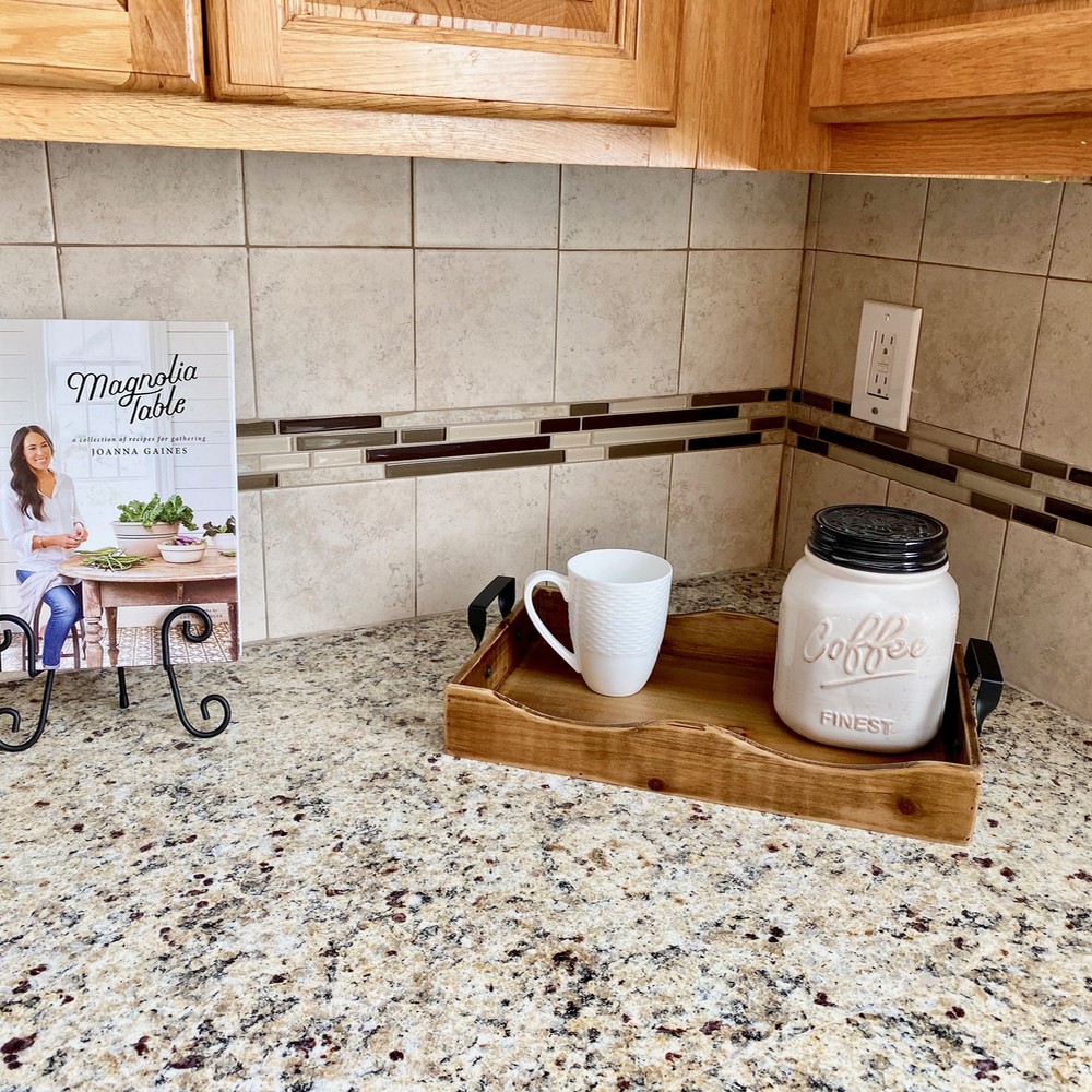 Kitchen counter top with cookbook, coffee cup, and coffee container.
