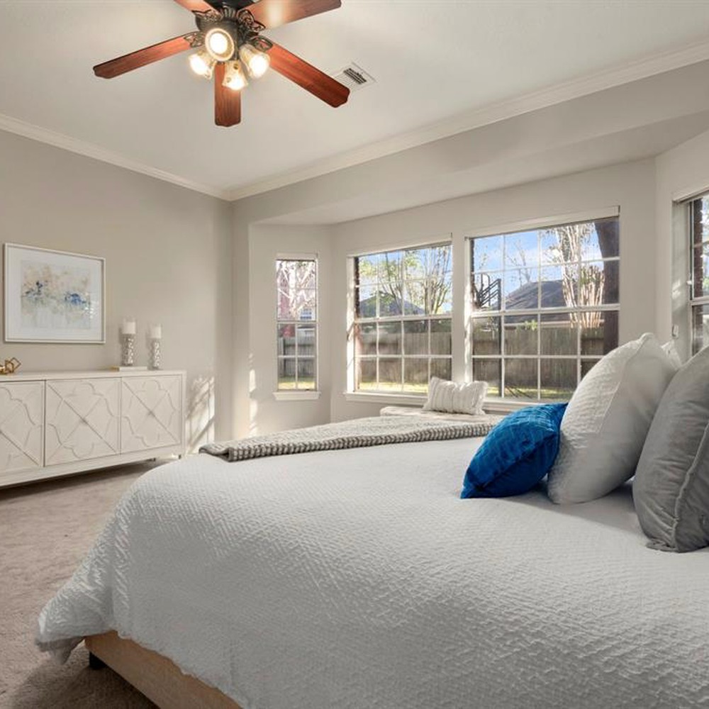 Primary bedroom with white comforter and blue pillows. White console with candles, and blue artwork.