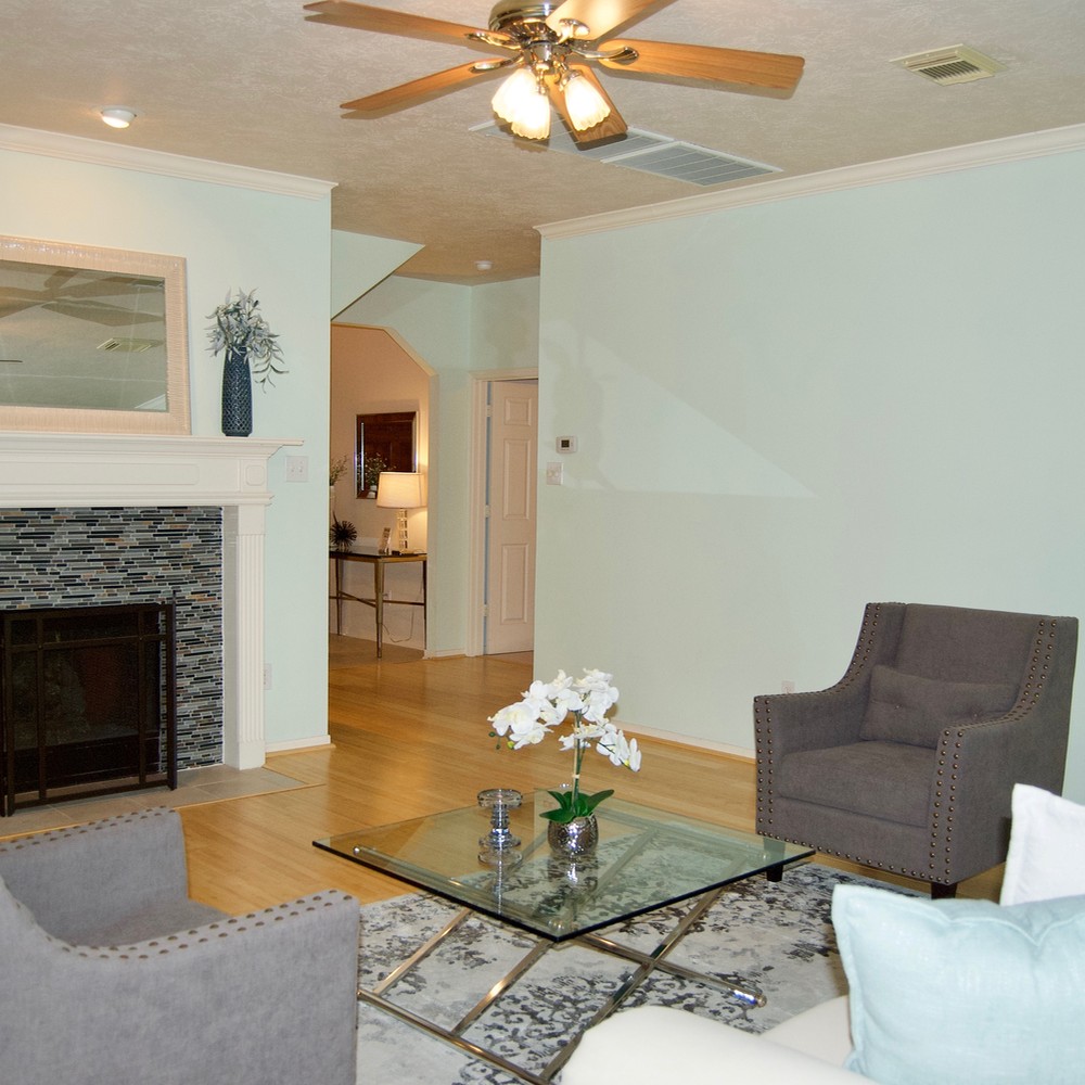 Living room with glass coffee table, white flower, and two gray chairs.
