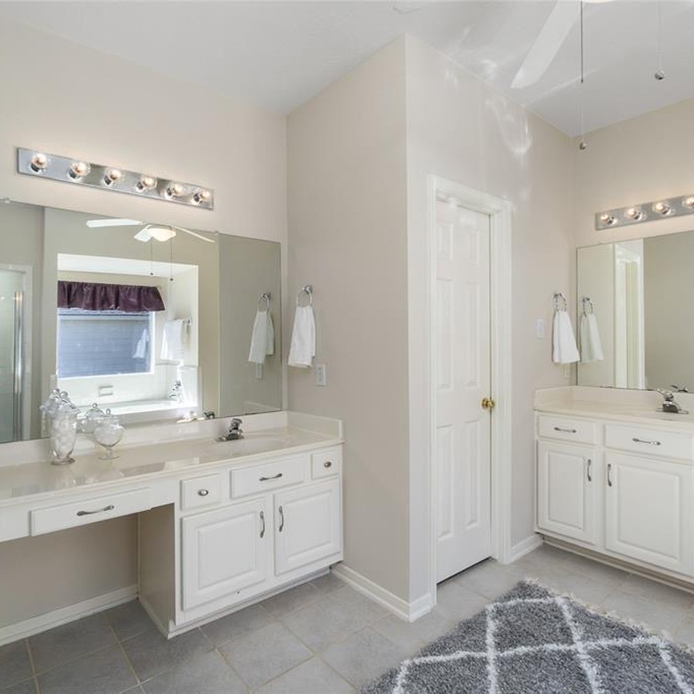 Bathroom with gray rug. Accessories placed around the counters.