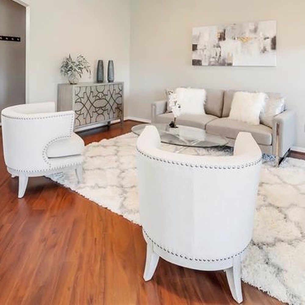 Living room with white rug, two white chairs, and light gray sofa. Console table with two vases and a plant.