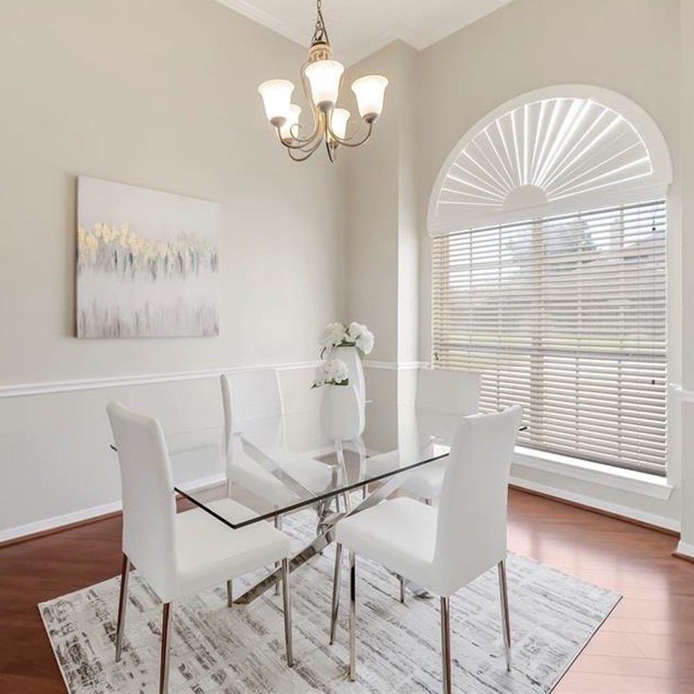 Dining room with glass table and four white chairs.