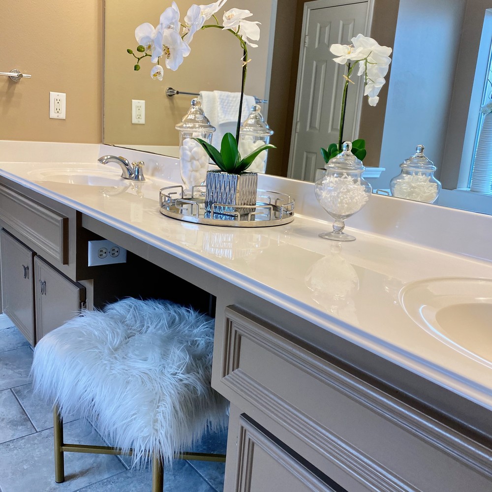 Primary bathroom with white stool. Orchid with silver vase.