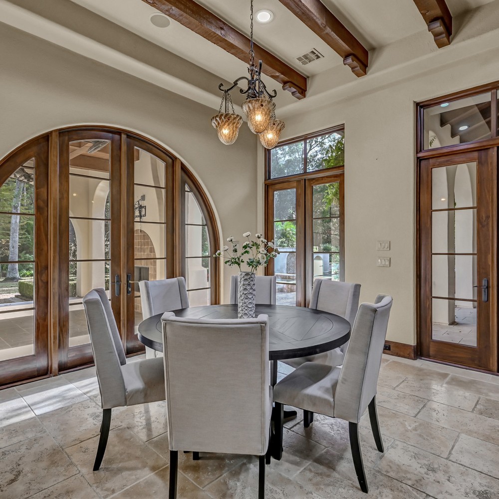 Black breakfast table with six chairs, and white vase and flowers.
