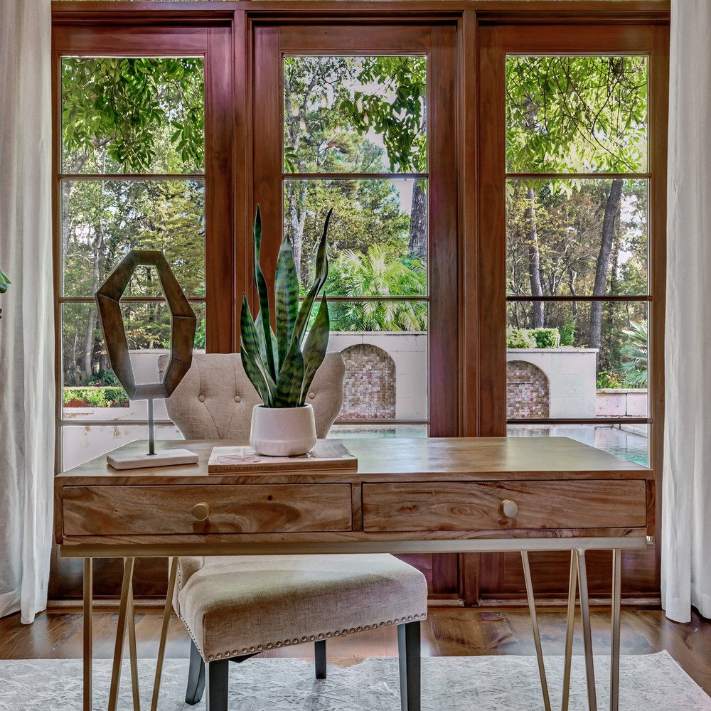 Wooden desk with gold legs. Plant on top of desk. View of the outdoor pool.