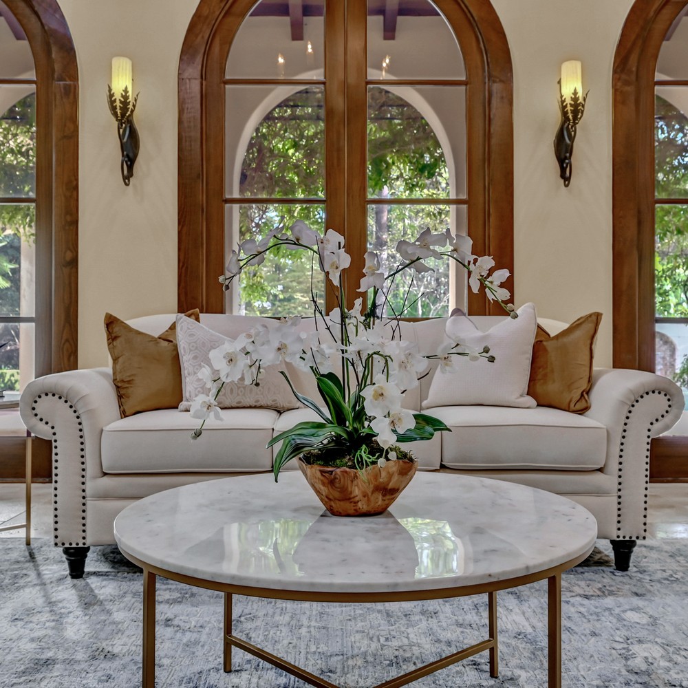Coffee table with marble top and golden frame. Wooden flower vase with white orchids.