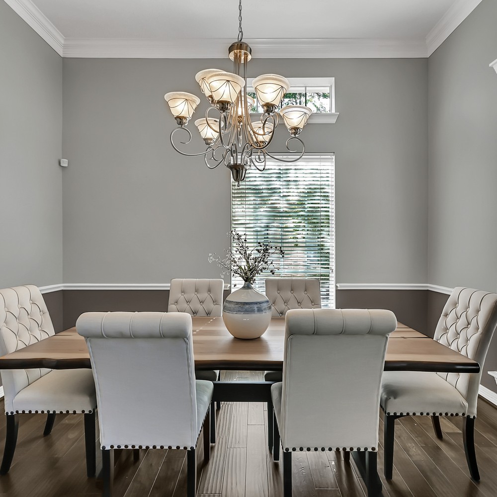 Dining room with living edge wooden table, blue vase with white flowers, and six white chairs