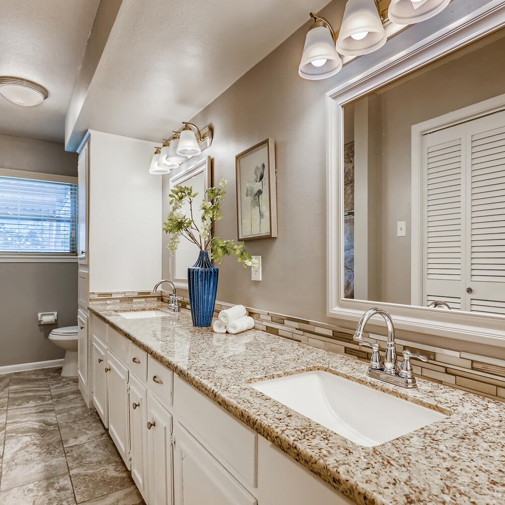 Bathroom vanity with white towels, blue vase, and white flowers.