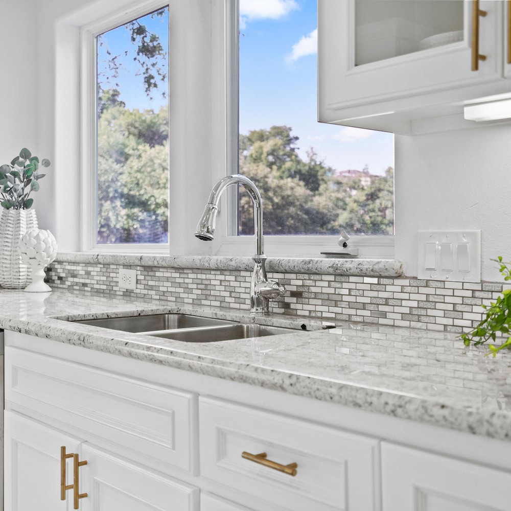 Close up of kitchen with greenery on either side of sink.