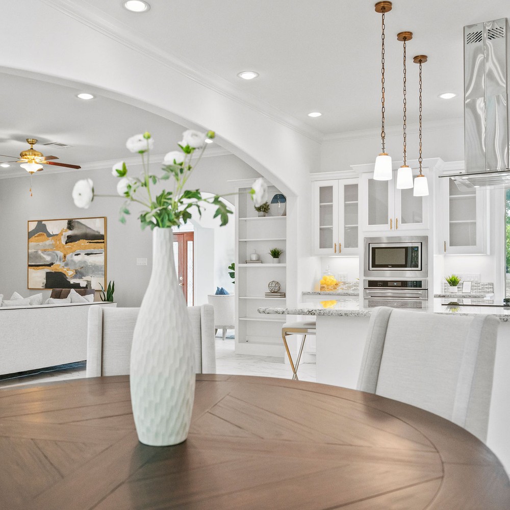 Dark wood breakfast table with white vase and flowers.