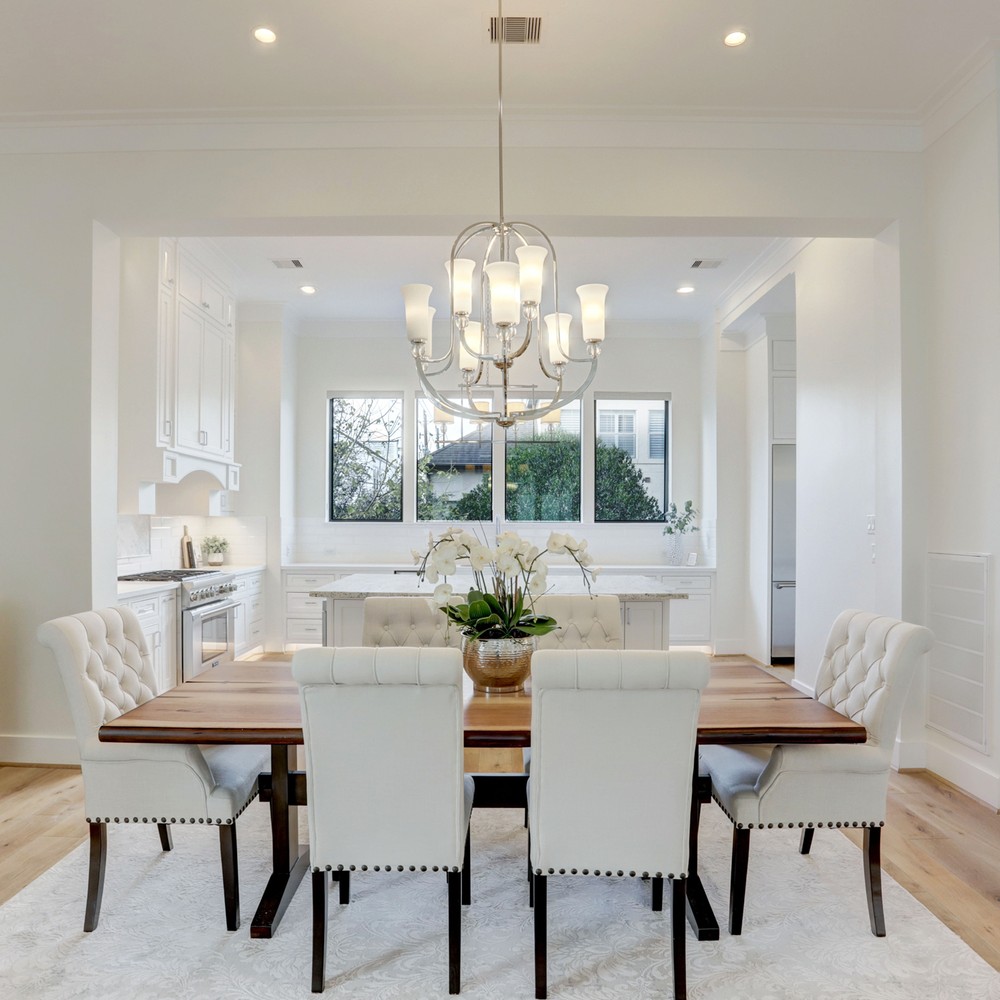 Dining room with wood table and six white chairs. Flower arangement on top of table.