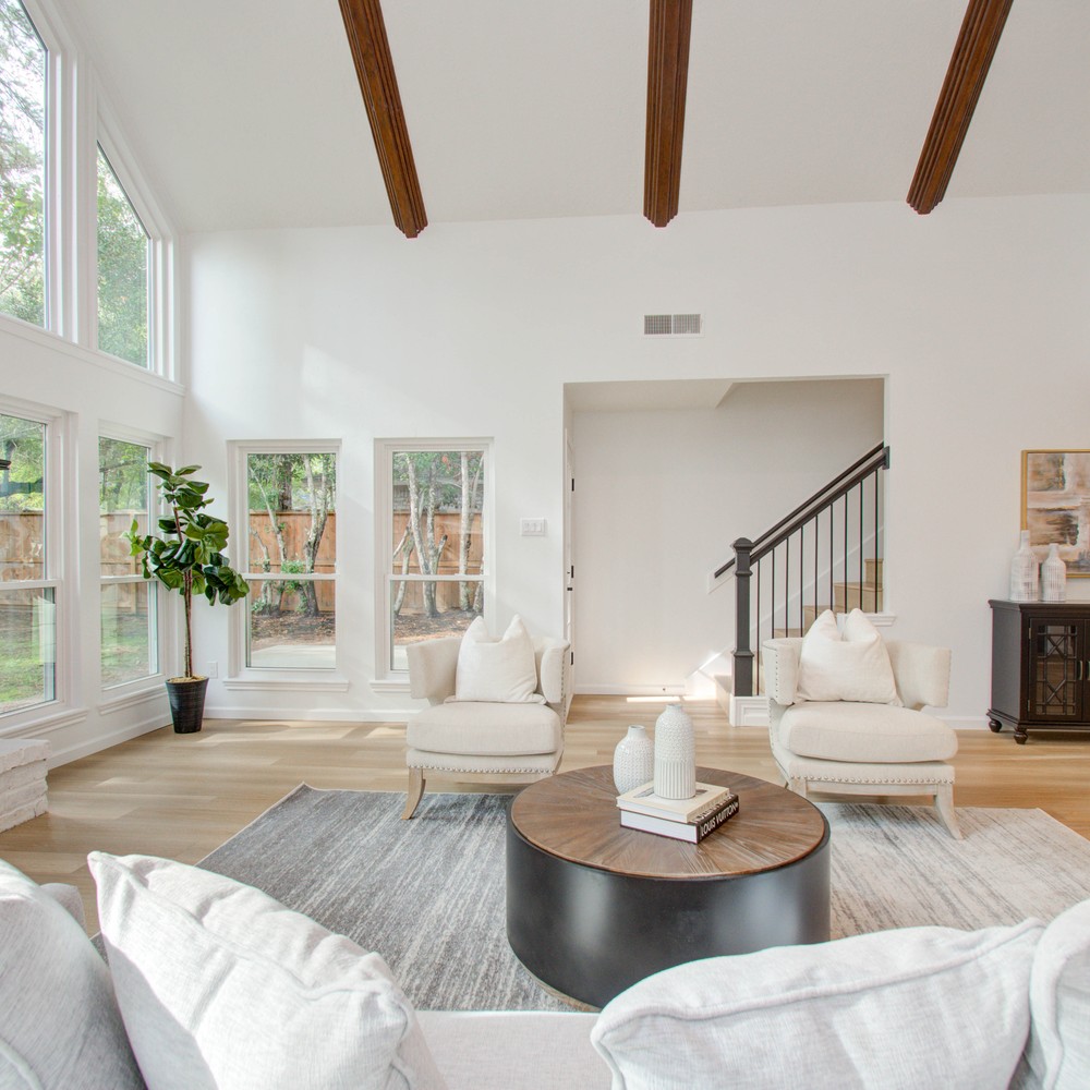 Living room with sofa, coffee table, chairs and accents showing the stairs and entry.