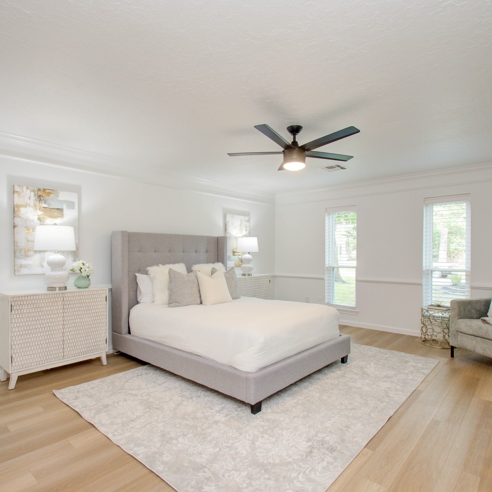 Bedroom with grey bed and white nightstands and seating area.