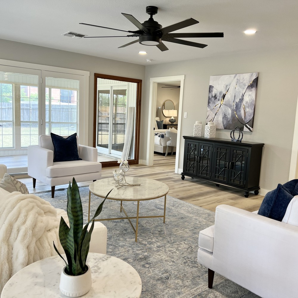 Living room with blue rug, two white chairs, and black console.