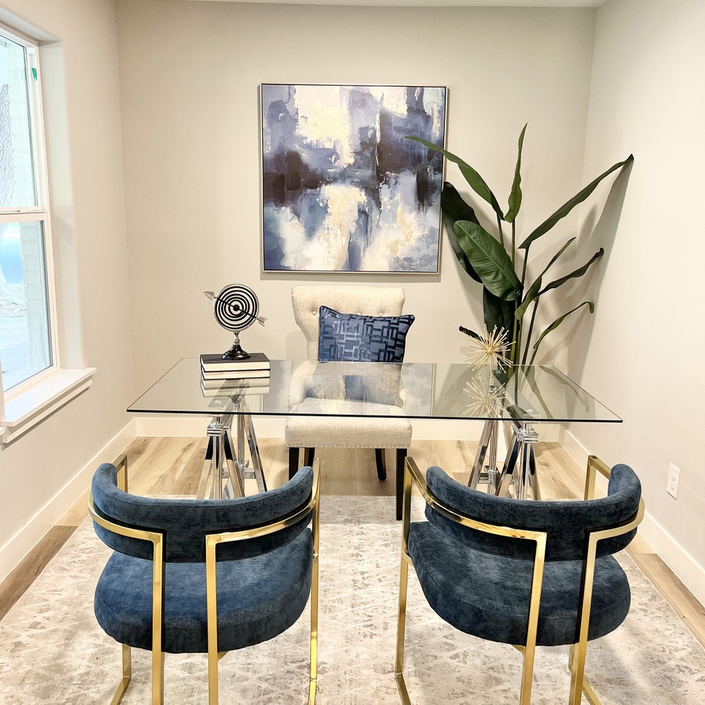 Office with blue and gold chairs in front of glass desk.