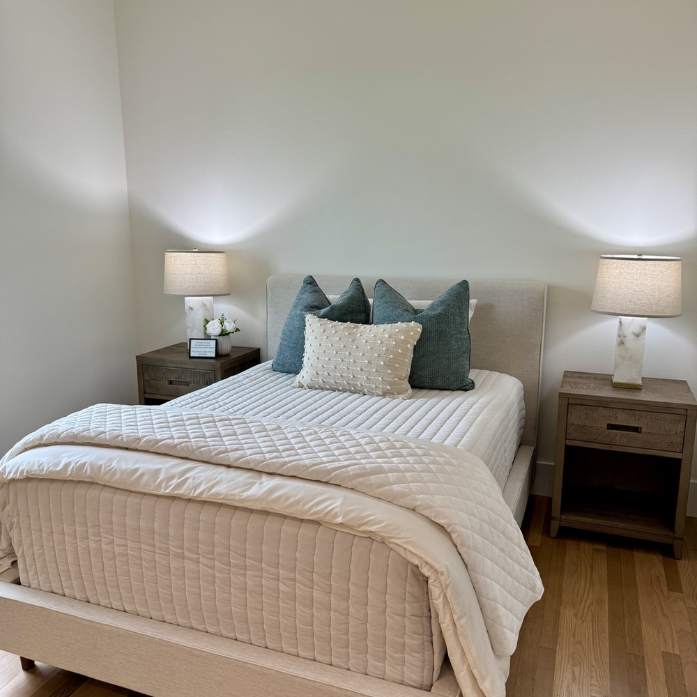 Round Top, TX Home Staging Secondary Bedroom with warm upholstered bed and wooden nightstands.