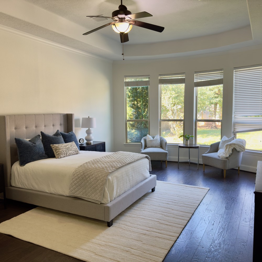 The Woodlands Home Staging: Primary Bedroom with gray bed and two chairs.